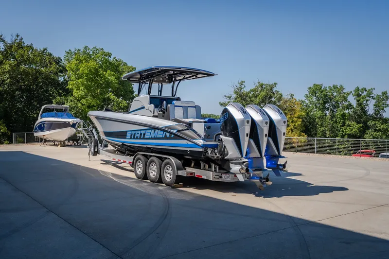 Slide: The Image of 2022 Statement 350 Open boat with triple engines on a trailer, parked outdoors. - 51