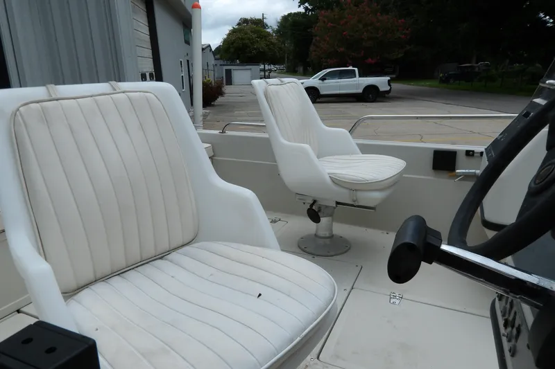Slide: The Image of 1991 Boston Whaler SL16 boat interior with white cushioned seats and steering wheel. - 16