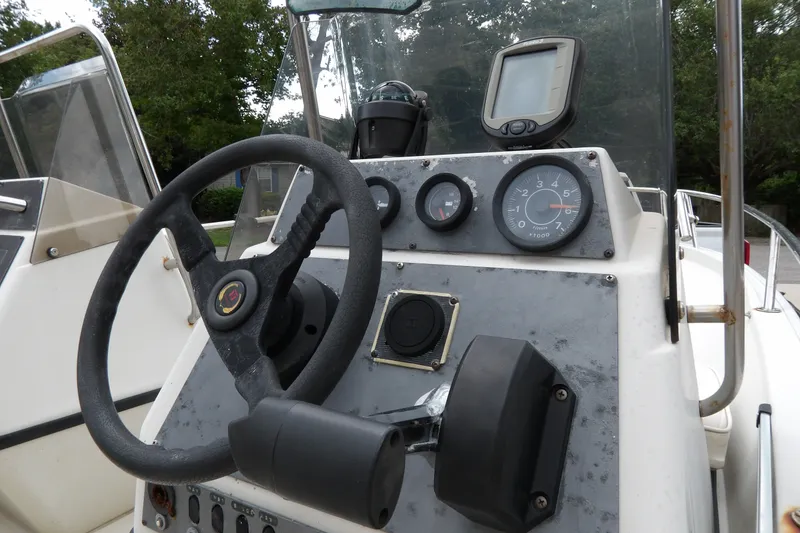 Slide: The Image of 1991 Boston Whaler SL16 boat dashboard with steering wheel and gauges. - 21