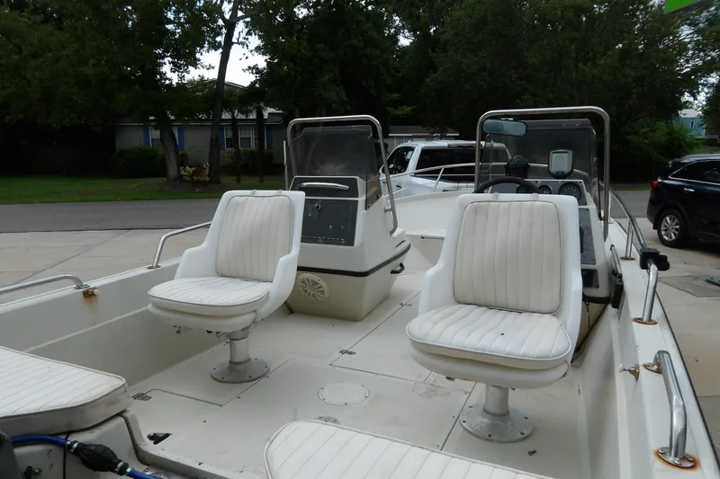 Slide: The Image of 1991 Boston Whaler SL16 boat interior with white cushioned seats and steering console. - 20