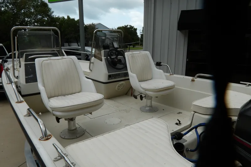 Slide: The Image of 1991 Boston Whaler SL16 boat interior with white seating and steering console. - 19