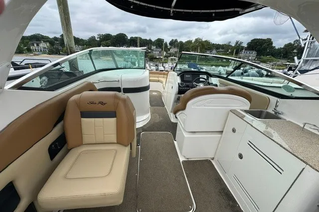 Slide: The Image of 2016 Sea Ray 300 SLX boat interior with tan seating, helm, and kitchenette. - 9