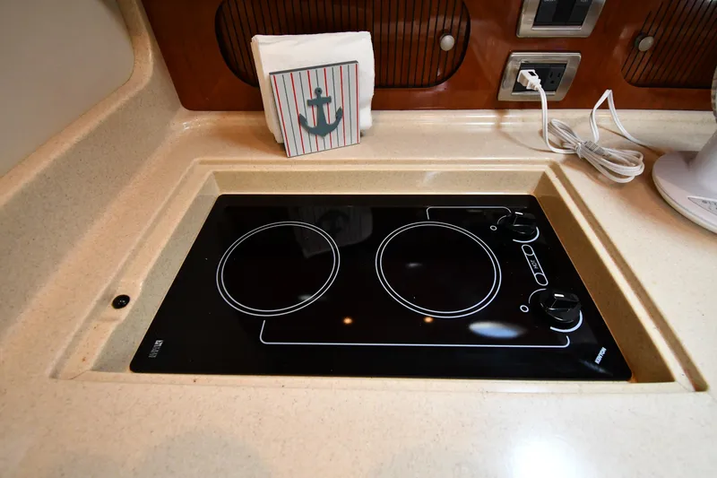 Slide: The Image of 2004 Sea Ray 360 Sundancer kitchen with electric stove and nautical-themed decor. - 47