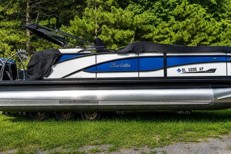 Slide: The Image of 2023 Barletta Corsa 21Q pontoon boat on grass, covered, with trees in background. - 2