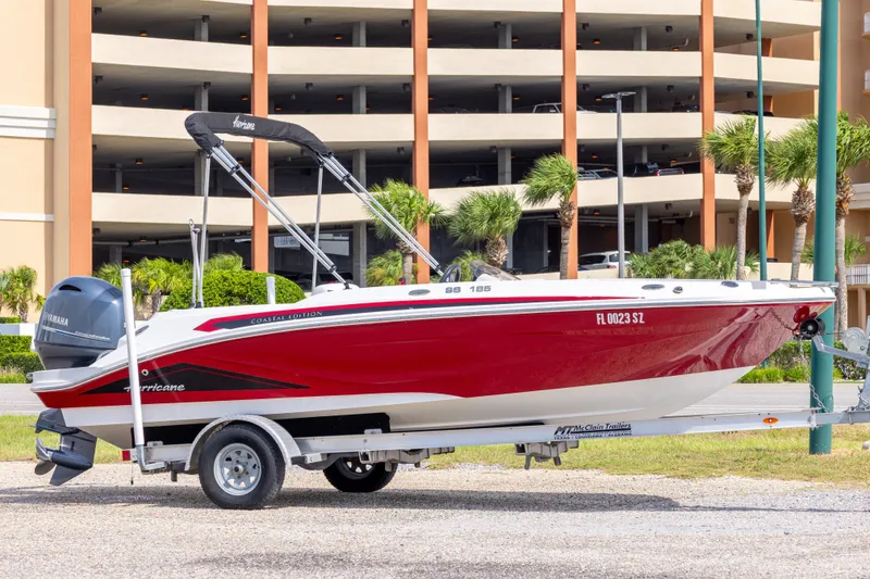 The Image of 2021 Hurricane SunDeck Sport 185 OB boat on trailer, red and white design, parked outdoors. - 0