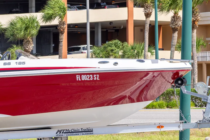 Slide: The Image of 2021 Hurricane SunDeck Sport 185 OB boat on trailer, parked near palm trees. - 16