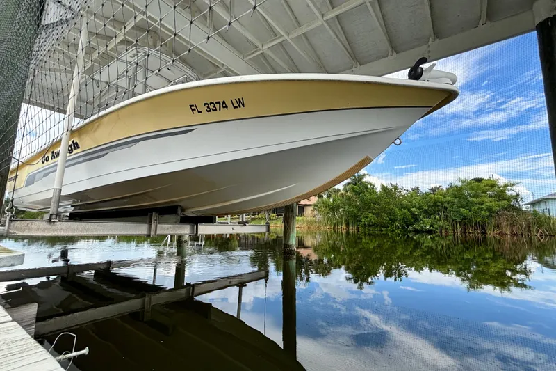 Slide: The Image of 2002 Ranger 2300 Bay Ranger boat docked above calm water under a covered structure. - 23