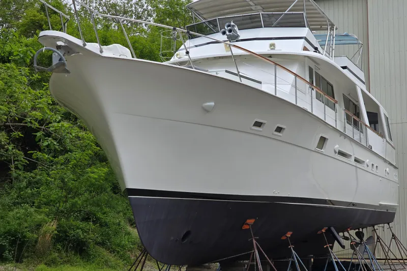 Slide: The Image of 1980 Hatteras 70 Motor Yacht on stands, surrounded by greenery and a building. - 29