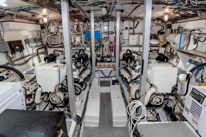 Slide: The Image of Engine room of a 1980 Hatteras 70 Motor Yacht, showcasing dual engines and complex wiring. - 27