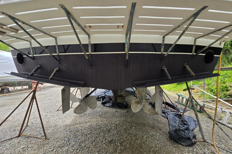 Slide: The Image of Stern view of a 1980 Hatteras 70 Motor Yacht on dry dock, showcasing propellers and rudders. - 42