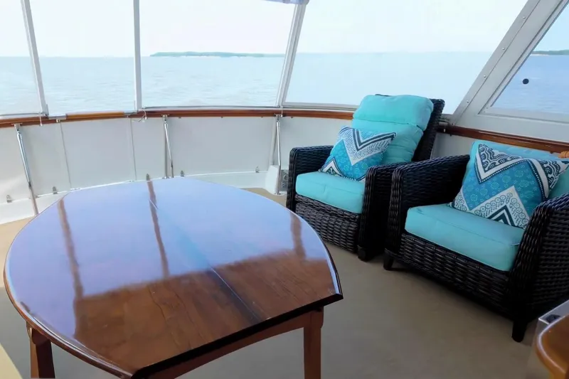 Slide: The Image of Luxurious 1980 Hatteras 70 Motor Yacht interior with ocean view, wicker chairs, and wooden table. - 13