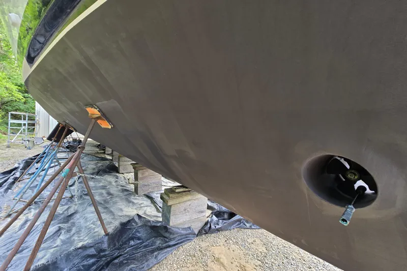 Slide: The Image of 1980 Hatteras 70 Motor Yacht hull on stands, undergoing maintenance in a yard. - 52