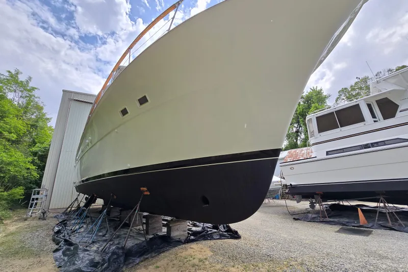 Slide: The Image of 1980 Hatteras 70 Motor Yacht on dry dock, side view under cloudy sky. - 50