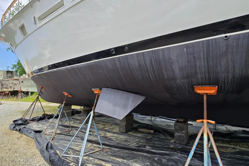 Slide: The Image of 1980 Hatteras 70 Motor Yacht on stands, hull view, in a boatyard setting. - 48