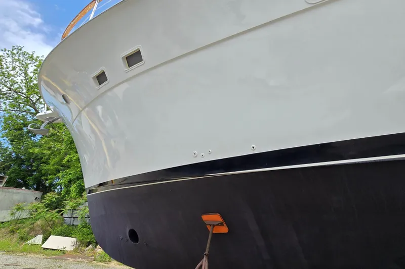 Slide: The Image of 1980 Hatteras 70 Motor Yacht hull, docked with trees in the background. - 49