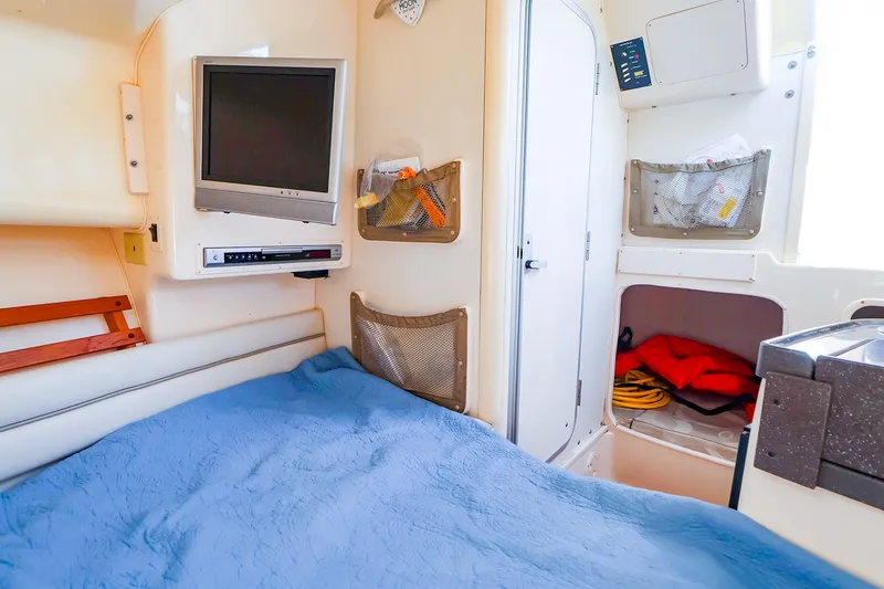 Slide: The Image of 2015 Grady-White Sailfish 282 cabin interior with bed, TV, and storage compartments. - 39