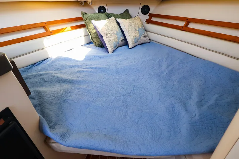 Slide: The Image of Cozy cabin interior of 2015 Grady-White Sailfish 282 with blue bedding and decorative pillows. - 30