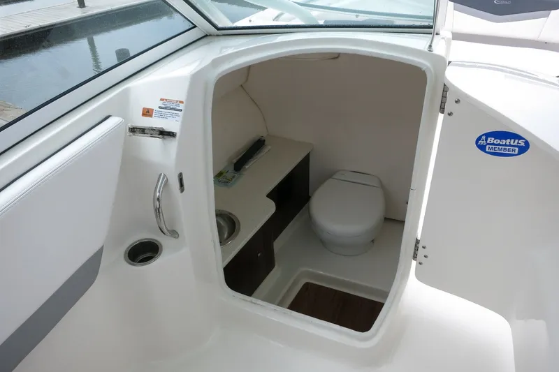 Slide: The Image of 2020 Robalo R247 Dual Console boat interior with compact marine toilet and sink. - 17