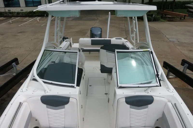 Slide: The Image of 2020 Robalo R247 Dual Console boat with open seating and windshield, docked on pavement. - 24