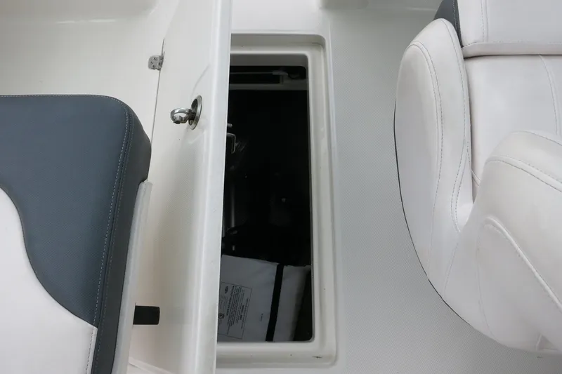 Slide: The Image of 2020 Robalo R247 Dual Console storage compartment with white and gray seating. - 16