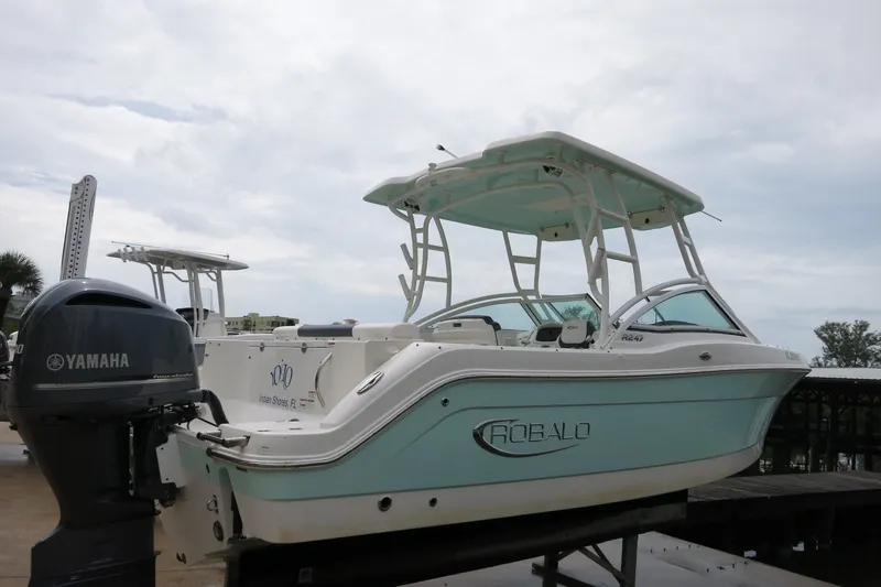 Slide: The Image of 2020 Robalo R247 Dual Console boat with Yamaha engine, docked under cloudy skies. - 1
