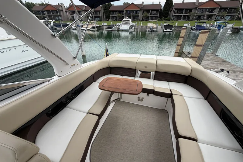 Slide: The Image of 2016 Regal 2700 ES Bowrider interior with beige seating and wooden table at marina. - 31
