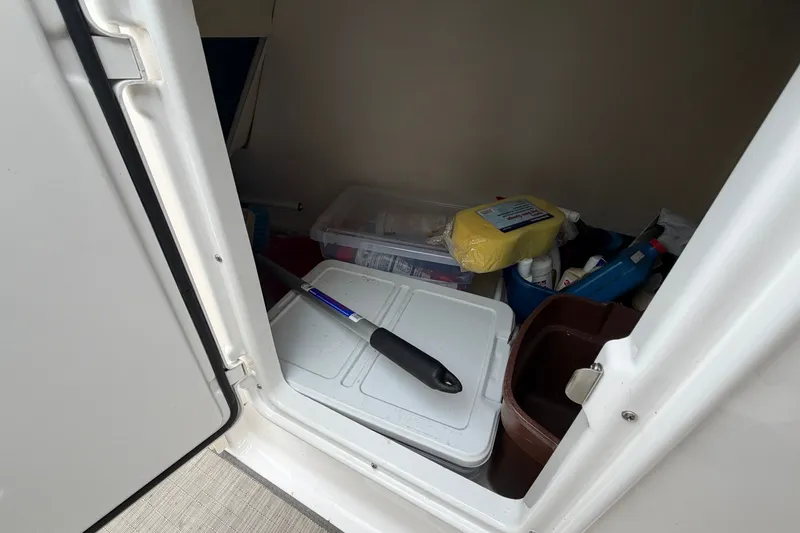 Slide: The Image of Storage compartment in a 2016 Regal 2700 ES Bowrider with cleaning supplies and tools. - 26