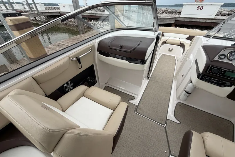 Slide: The Image of 2016 Regal 2700 ES Bowrider interior with beige seating and modern dashboard at a dock. - 15