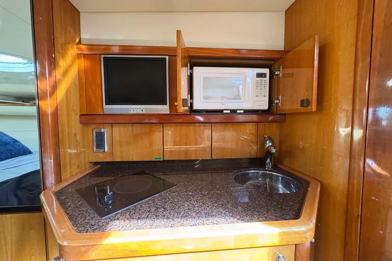 Slide: The Image of 2004 Sunseeker Sportfisher 37 yacht kitchen with microwave, TV, stove, and sink. - 106