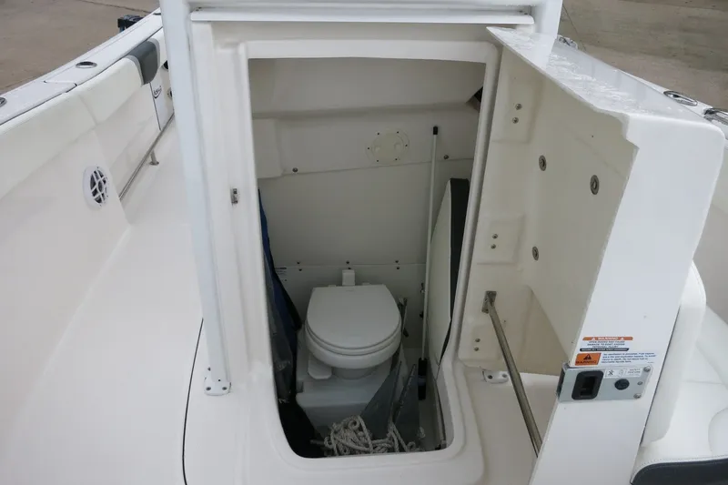 Slide: The Image of 2022 Robalo R230 Center Console boat interior with open compartment showing marine toilet. - 18