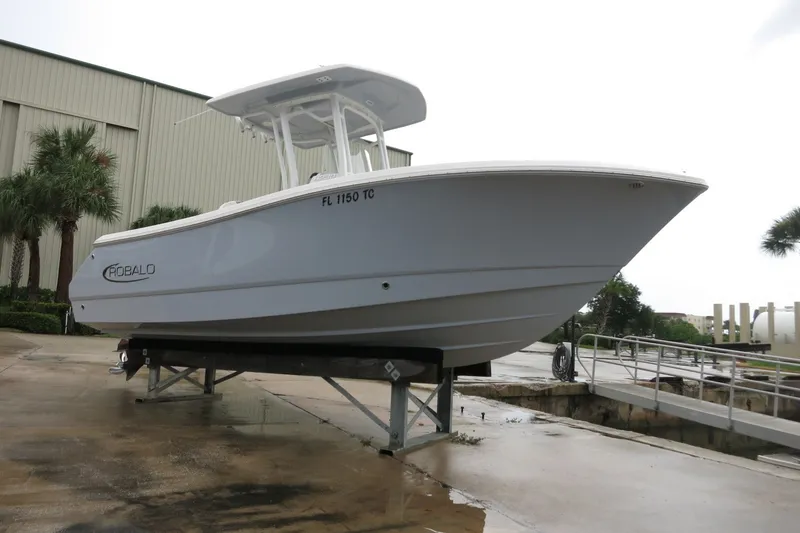 Slide: The Image of 2022 Robalo R230 Center Console boat on a lift, near a warehouse and palm trees. - 1