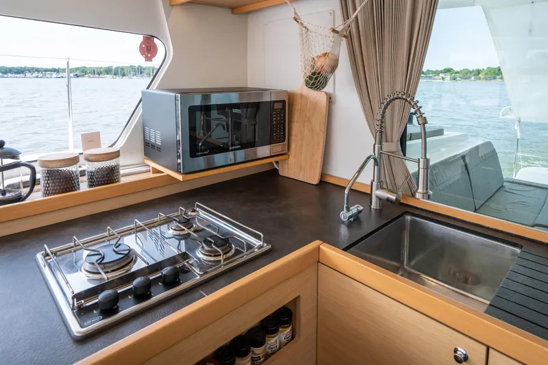 Slide: The Image of The galley of a 2017 Lagoon 42 with a stove, sink, and microwave. - 22