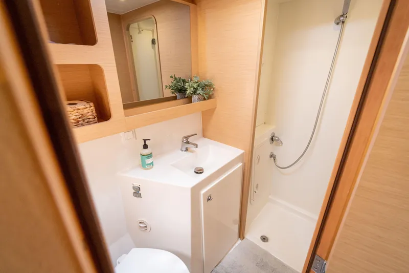 Slide: The Image of The image shows a modern boat bathroom with a sink, shower, and wood paneling. - 46