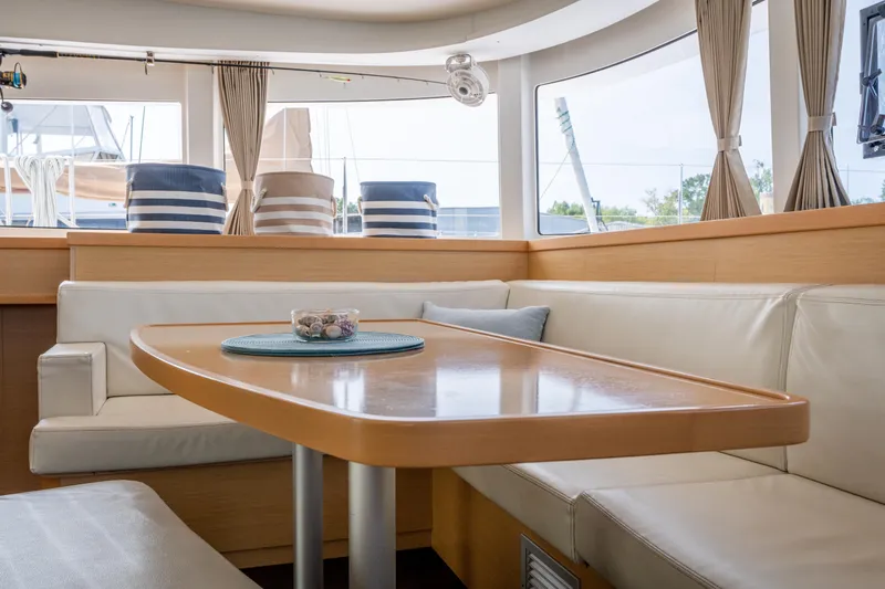 Slide: The Image of The interior of a 2017 Lagoon 42 features a cozy seating area with a wooden table and beige upholstery. - 17