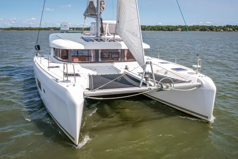 Slide: The Image of A white 2017 Lagoon 42 catamaran sails on calm waters under a blue sky. - 13