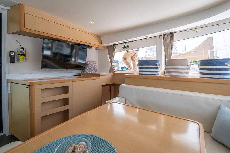 Slide: The Image of The interior of a 2017 Lagoon 42 features a modern seating area with a table and a TV. - 25