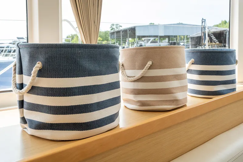 Slide: The Image of Three striped fabric baskets with rope handles sit on a wooden shelf in a boat interior. - 40
