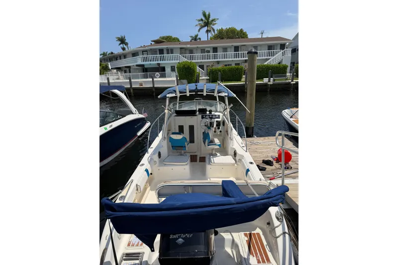 Slide: The Image of 2002 Sea Fox 230 Walk Around boat docked at marina, featuring spacious deck and seating. - 7