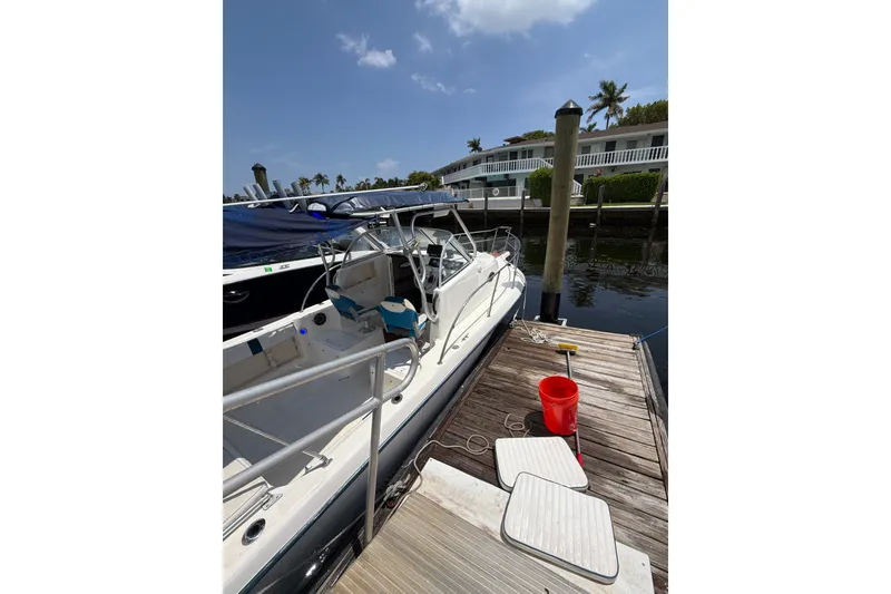 Slide: The Image of 2002 Sea Fox 230 Walk Around boat docked, with clear skies and waterfront view. - 4