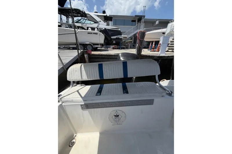 Slide: The Image of 2002 Sea Fox 230 Walk Around boat interior with seating and docked vessels in background. - 12