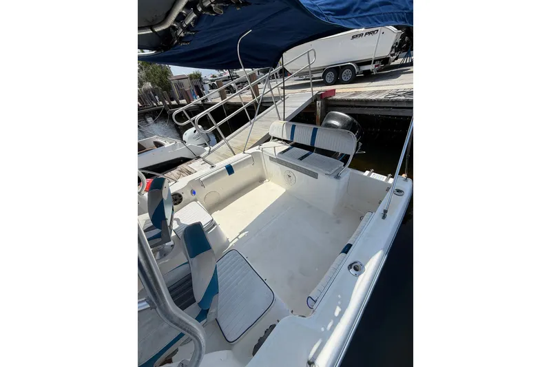 Slide: The Image of 2002 Sea Fox 230 Walk Around boat interior with seating and canopy at dockside. - 33