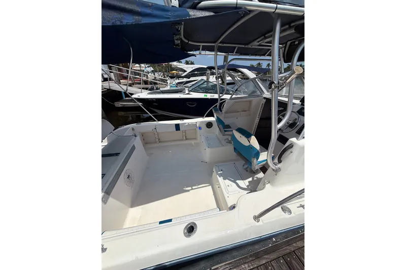 Slide: The Image of 2002 Sea Fox 230 Walk Around boat interior at marina, featuring seating and helm. - 3