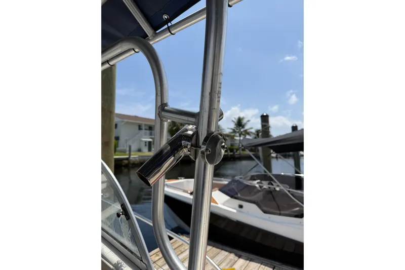 Slide: The Image of Close-up of a 2002 Sea Fox 230 Walk Around boat's metal railing, docked near waterfront homes. - 27