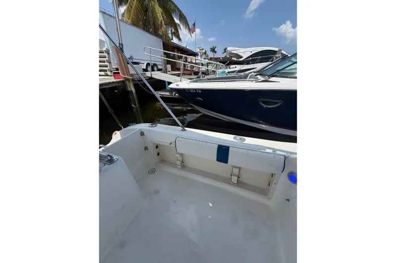 Slide: The Image of 2002 Sea Fox 230 Walk Around boat docked near palm trees and other vessels. - 13