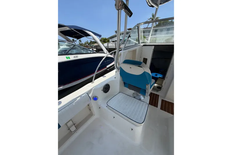 Slide: The Image of 2002 Sea Fox 230 Walk Around boat interior with seating and cabin entrance. - 14