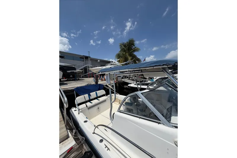 Slide: The Image of 2002 Sea Fox 230 Walk Around boat docked under a clear blue sky. - 8