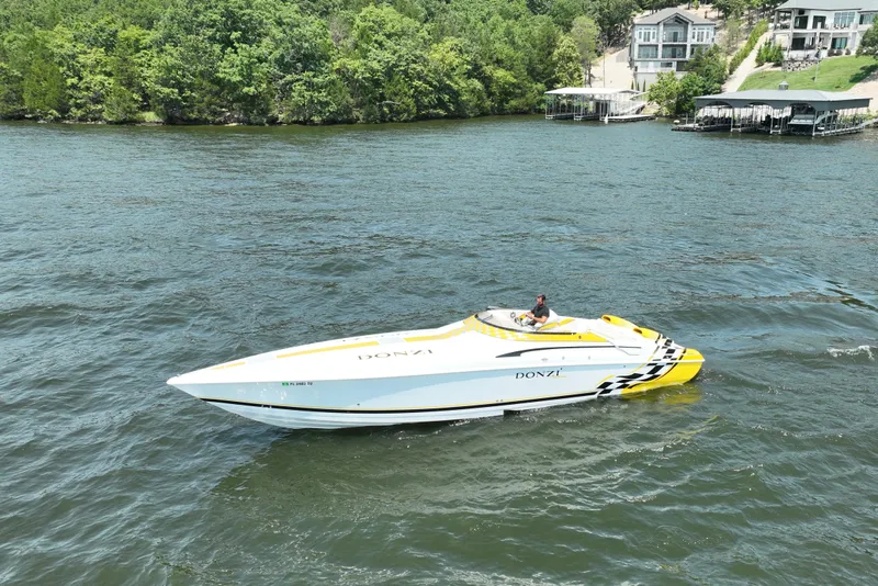 Slide: The Image of 2002 Donzi 38 Daytona speedboat cruising on a scenic lake with lush greenery. - 1