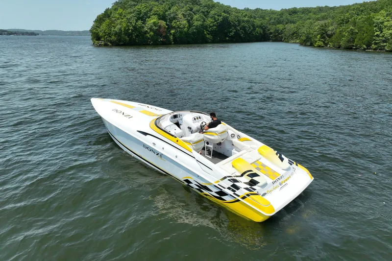 Slide: The Image of 2002 Donzi 38 Daytona speedboat on a scenic lake with lush green shoreline. - 10