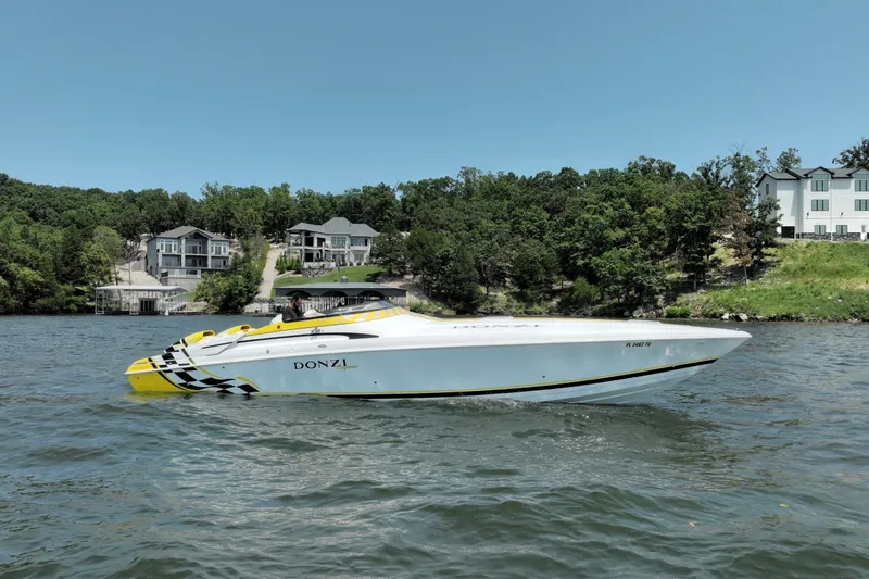 Slide: The Image of 2002 Donzi 38 Daytona speedboat cruising on a lake with waterfront homes in the background. - 26