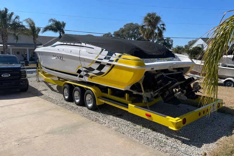 Slide: The Image of 2002 Donzi 38 Daytona boat on yellow trailer, parked outdoors with palm trees. - 23